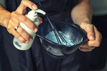 Hairdresser calorist mixes ingredients for hair coloring.