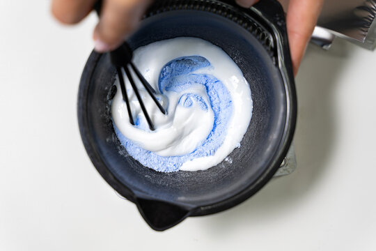 Hairdresser colorist kneads paint for hair dyeing. The concept of the salon barbershop.