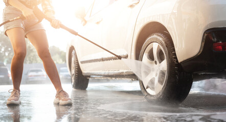 Girl using pressure water on self service car wash