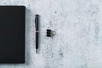 Black Notepad with a black pen on a gray background.