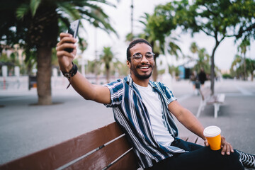 Cheerful man taking picture on bench