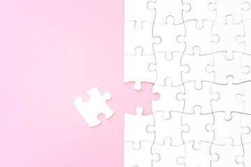Last unconnected piece of white puzzle on pink background