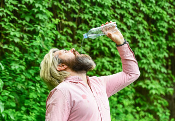 Soda water. Water balance. Man bearded tourist drinking water plastic bottle nature background....