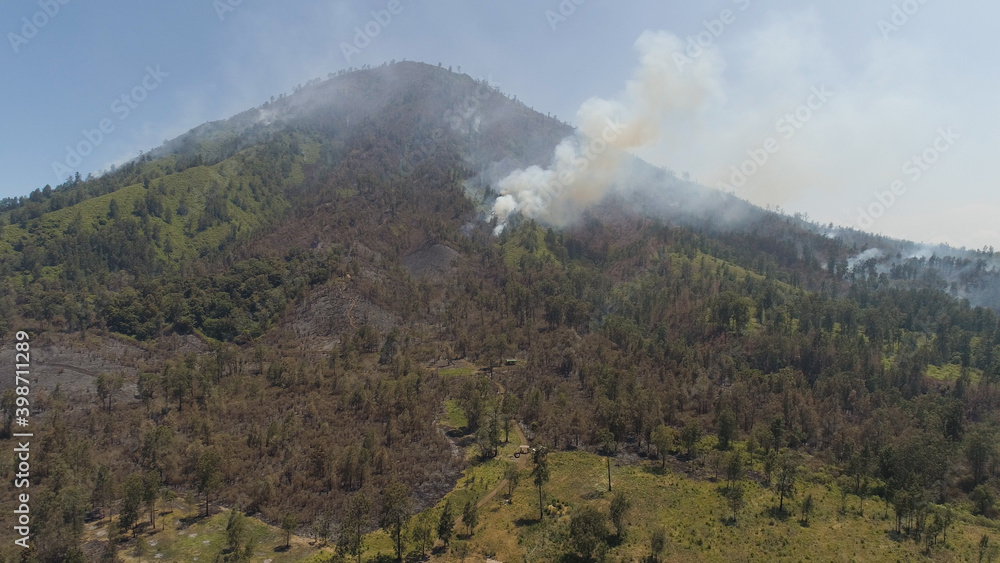 Wall mural aerial view forest fire smoke on the slopes hills. fire in mountain forest. wild fire in tropical forest, Java Indonesia. natural disaster fire in Southeast Asia - Wall murals
