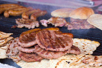 Traditional serbian street food (rostilj) - pljeskavica, cevapi, grilled chicken breast, bbq chicken wings and homemade sausages served with fresh bakery (lepinja)