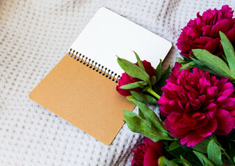 notebook with flowers of pink red peonies on a gray background on the bed