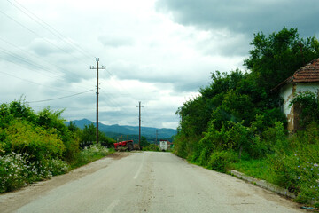 Fototapeta na wymiar Scenic asphalt countryside road across the poor villages of Southern Serbia on a rainy day