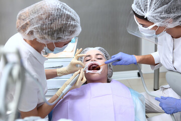 Professional teeth cleaning. A young girl at a dentist appointment. Retractor and saliva pump in...