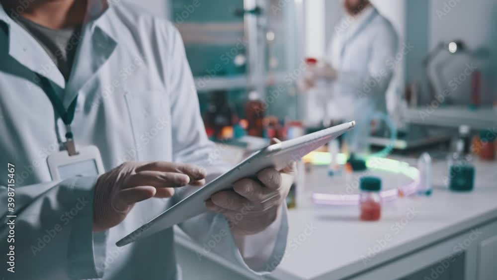 Wall mural close-up of lab worker using digital tablet at workspace. male scientist expert browsing technology 