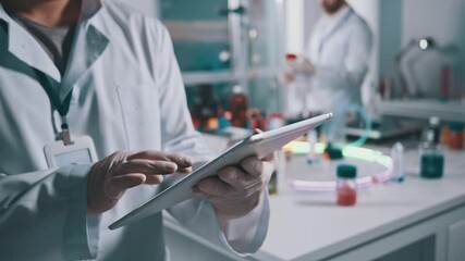 Close-up of lab worker using digital tablet at workspace. Male scientist expert browsing technology device collaborating in medical research laboratory. - Powered by Adobe
