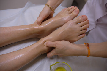 Massage room. Girl's legs close up. Masseur's hands. Acupressure. White background.