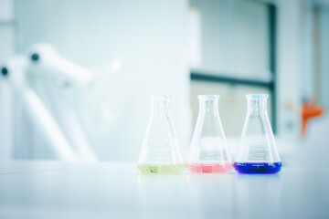 Laboratory flask with colorful liquids stirred inside in laboratory