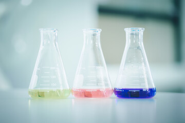 Laboratory flask with colorful liquids stirred inside in laboratory