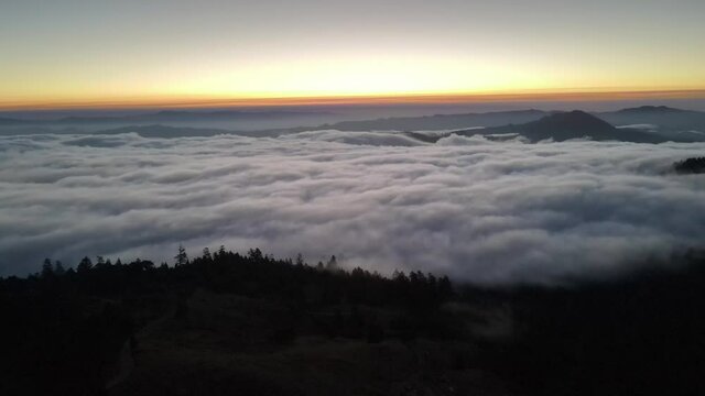 flying over clouds in the mountains at sunrise