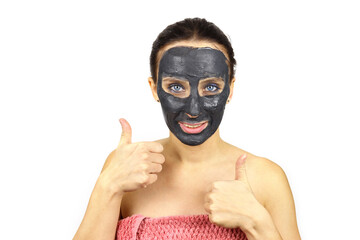 Beautiful girl in a cosmetic mask on her face shows a like gesture