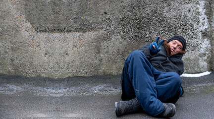 The homeless man, leaning on his elbow, lies and shows a sign of victory on his fingers.