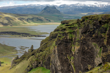 Icelandic landscape with volcanic lava ridge, glacier mountains, green grass. Vik area, Iceland