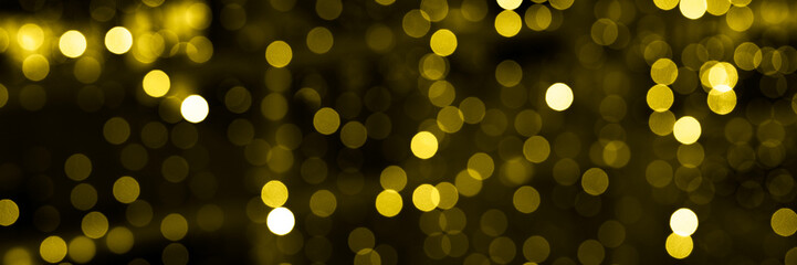 blurred glowing lights of garlands of golden color, bokeh. banner. toned in illuminating and ultimate gray, trend color of the year 2021