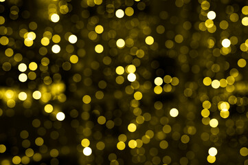 blurred glowing lights of garlands of golden color, bokeh. toned in illuminating and ultimate gray, trend color of the year 2021