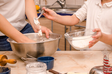 Hands of mother and daughter prepare festive gingerbread cookies for christmas, daughter pours flour on dough