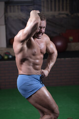 Male bodybuilder posing in the gym. Male athlete shows off his figure