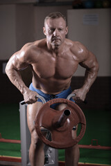 Fototapeta na wymiar A male athlete works out on simulators and trains his muscles. Bodybuilding classes