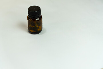 brown bottle of remedy with pills inside on white background