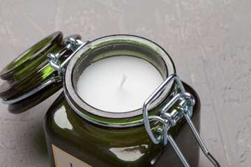 Scented candle in a glass jar on a background of kraft paper, green leaves and a pine cone. Light text background