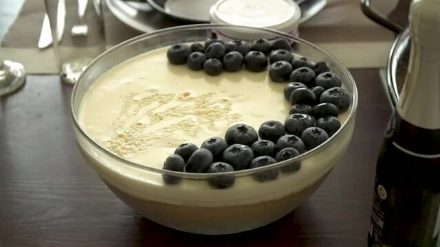 Close up of delicious cheesecake with blueberries on top served with champagne and a sparkling wine bottle in a kitchen.