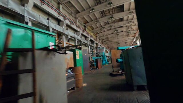 Aerial, FPV, drone shot flying inside from the door of an old car manufactoring facility hall