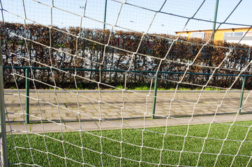 Fototapeta premium Closeup of a soccer goal net on a field of green artificial grass 