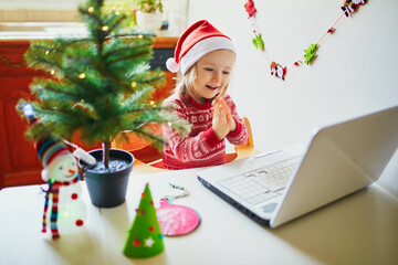 Kid using computer to communicate with friends or elderly relatives on Christmas or New Year