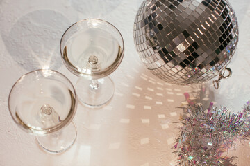 Glass of champagne in a coupe with disco ball and sparkles. New Year party, birthday, girls day or other celebration event