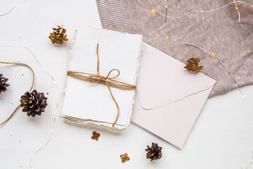 Cozy hygge style flat lay. Christmas wish list. Handmade paper tied with craft thread. Letter envelope, pine cones, craft thread and candle. , top view.