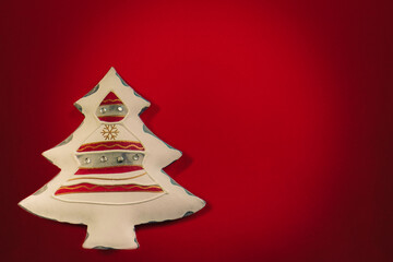 New Year's white toy in the form of a stylized Christmas tree on a dark red background