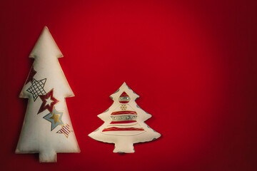 Fototapeta na wymiar Two New Year's white toys in the form of a stylized Christmas tree on a dark red background