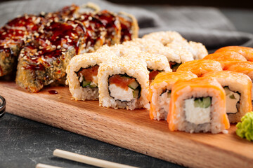 Closeup on assorted sushi rolls on a wooden board with wasabi and soy sauce