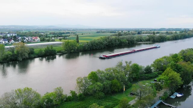 Aerial view of a Inland waterway shipping, freight transport on Main river, in Raunheim village, Germany - static, drone shot