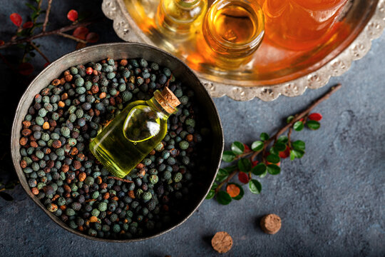 Small bottle of  oil lays horizontally on the Pistacia terebinthus oil. Pistacia terebinthus oil and dried seeds on dark wooden background.
