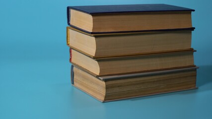 books are placed on top of each other on a blue background. concept of the benefits of reading and accumulation of knowledge