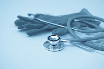 Stethoscope, medical mask and gloves on a light background. Toning. Close up.