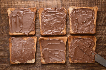 Toast with chocolate-nut paste spread on wooden background top view