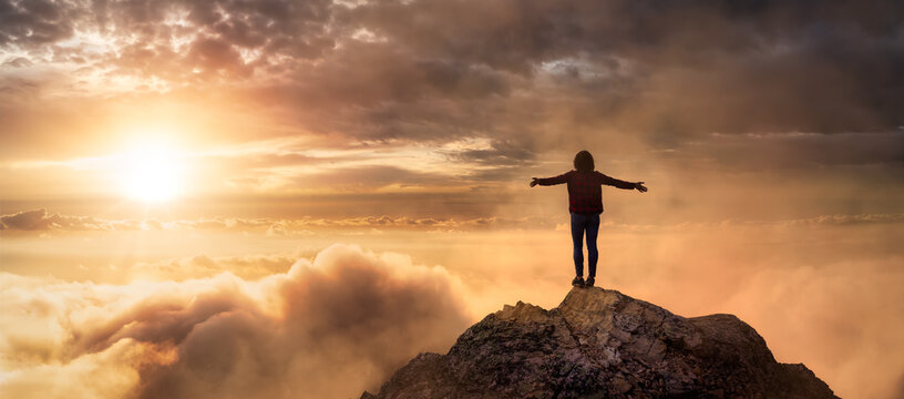 Fantasy Adventure Composite with a Girl on top of a Rock Cliff with Beautiful Nature in Background during Sunset or Sunrise. Landscape from British Columbia, Canada. Concept: Hike, Freedom, Journey
