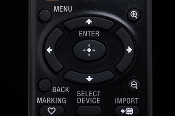 Black plastic remote control with menu and navigation buttons macro close up front view shot isolated on black