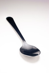 Simple silver metal spoon diagonally set on white large depth of field isolated