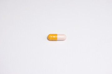 Yellow and white medical capsule pill horizontally laid on white macro close up shot