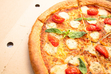 
Margarita pizza with mozzarella, cherry tomatoes and basil in cardboard box