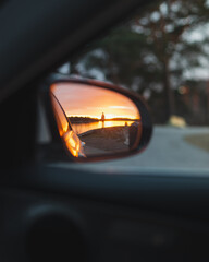 Sunset through car rear view mirror looking back