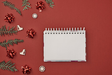 New Year's decor and a notebook in the center on a red background. Christmas decoration. Copy space, flat lay, mock up, top view