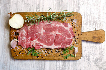 Fresh raw pork neck with spices on wooden board closeup, ingredients for a delicious meat meal